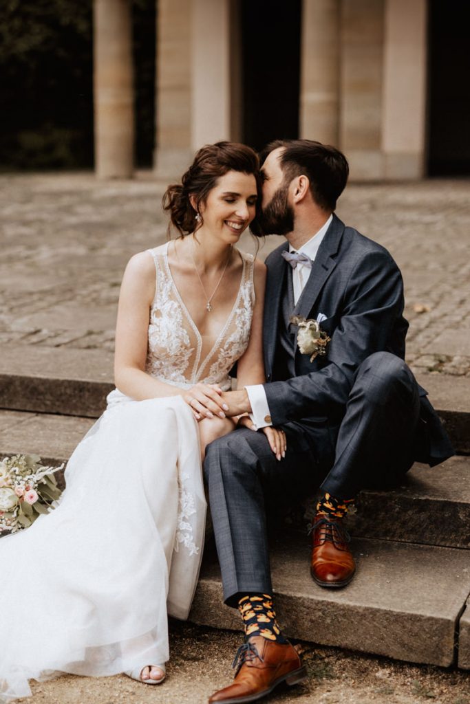 svg%3E hochzeitsfotograf wolfsburg hochzeit heiraten hochzeitsfoto brautpaar sitzend auf der treppe am schloss wolfsburg